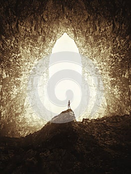 Man in giant cave with light coming from outside photo