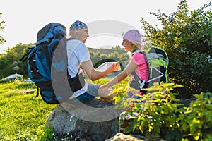 Man and girl with backpack resting and looking at map