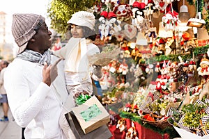 Man with girl buying Christmas decoration with tree leave at fair