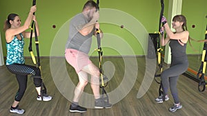 A man and a girl are engaged on the loops of the TRX performing exercises Bulgarian split-squat, strengthening the