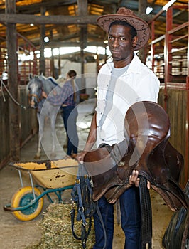 Man and girl harnessing horse in stable