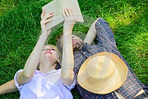 Man and girl lay on grass having fun. Couple in love spend leisure reading book. Couple soulmates at romantic date