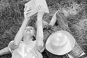 Man and girl lay on grass having fun. Couple in love spend leisure reading book. Couple soulmates at romantic date