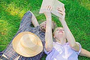 Man and girl lay on grass having fun. Couple in love spend leisure reading book. Couple soulmates at romantic date