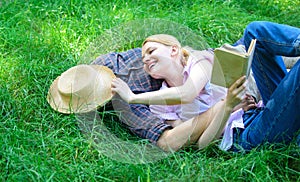 Man and girl lay on green grass having fun. Couple in love spend leisure reading book. Couple soulmates at romantic date