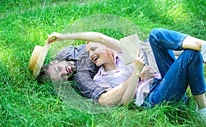 Man and girl lay on green grass having fun. Couple in love spend leisure reading book. Romantic couple students enjoy