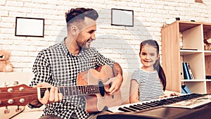 Man and Girl Play Piano. Play Guitar. Play Piano Together. Piano and Guitar. Father and Daughter on Sofa. Spend Time Together.
