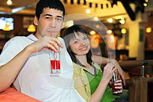 Man and girl sit and drink cocktail