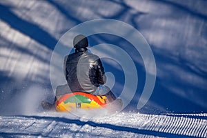 Man with daughter sledding down a snowy hill