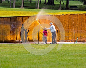 Man and girl washing wall at Vietnam memorial