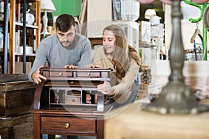 Man with girlfriend admiring vintage wooden bureau