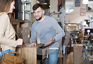 Man with girlfriend choosing vintage bedside table