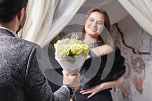 A man gives a bouquet of yellow roses to his beloved woman .