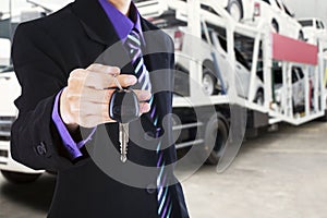 Man gives a car key with trailer truck background