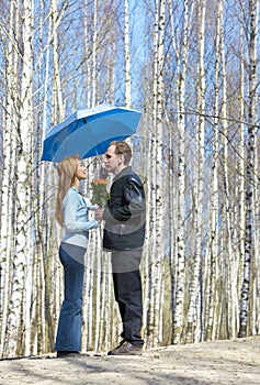 Man gives girl bouquet under umbrella