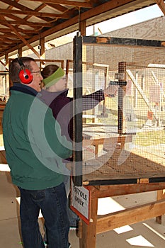 Man gives shooting tips to young woman at shooting range