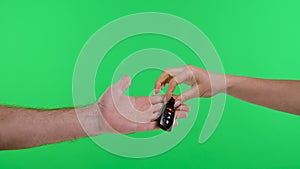 A man gives a woman a car. Close up of a man's hand giving a car remote control to a woman's hand against a green screen