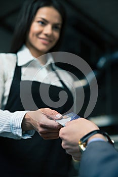 Man giving bank card to female waiter in cafe