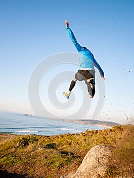 Man giving a big jump while practicing trail running