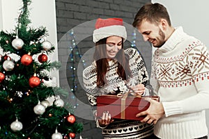 man giving big present to his woman. happy stylish family smiling at decorated christmas tree. joyful cozy moments in winter