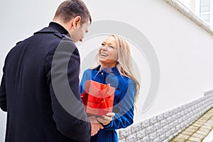 A man is giving a box with a gift to a woman.