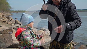 Man giving a caught fish to his granddaughter