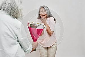 Man giving chamomile flowers to pleased woman