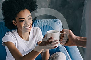 Man giving cup of coffee to african