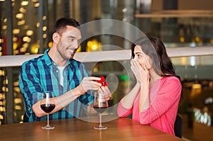 Man giving engagement ring to woman at restaurant