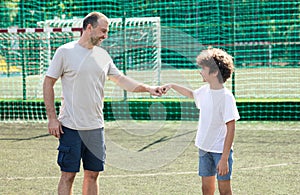 Man giving fist bump to boy ar football pitch