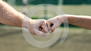 Man giving fist bump to son in nature background