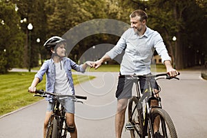 Man giving fist bump to son riding bicycles