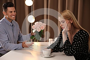 Man giving flowers to displeased woman in restaurant. Failed first date