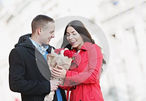 Man giving flowers to his girlfriend; young, romantic couple outdoors