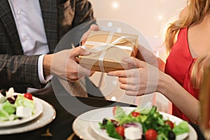 Man giving gift box to girlfriend on romantic dinner in restaurant