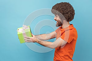 Man giving gift, congratulating on birthday and offering surprise, holiday bonus wrapped in box. photo