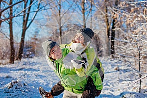 Man giving his girlfriend piggyback in winter forest. Couple in love having fun