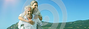 Man giving his laughing wife a piggy back at the beach