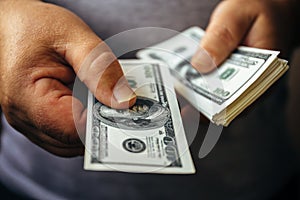 Man giving hundred us dollar banknote and holding cash in hands