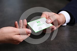 Man giving medical business card to woman on dark background. Nephrology service