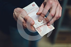 Man giving money, Russian Ruble banknotes, over his desk in a dark office - bribery and corruption concept.russian