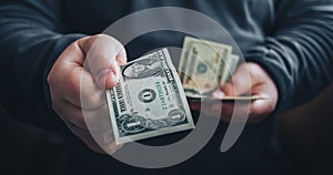 Man giving one us dollar banknote and holding cash in hands. Toned picture.