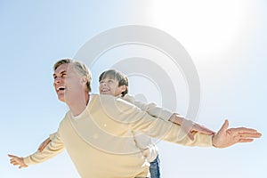 Man Giving Piggyback Ride To Son Against Clear Blue Sky