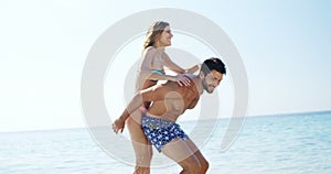 Man giving piggyback ride to woman at beach