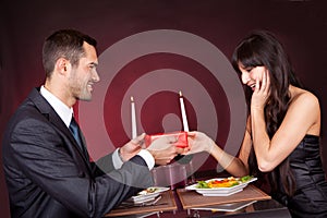 Man giving present to a woman in restaurant