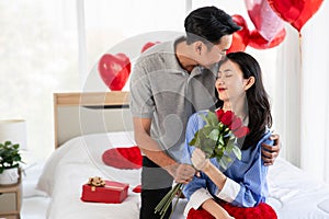 Man giving a rose and a kiss to his beautiful wife in bed Valentine`s Day  concept