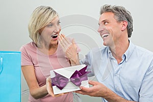 Man giving a surprised woman a birthday gift