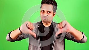 Man giving thumbs down gesture on green screen background expressing disapproval or negative feedback