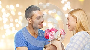 Man giving woman flowers over festive lights