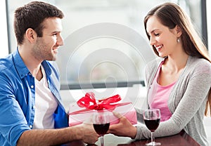 Man giving woman gift at cafe